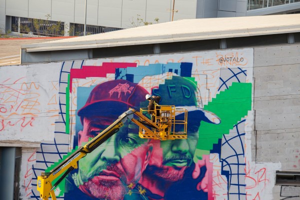 El artista de Alcantarilla Jota pinta un mural en una de las persianas del El Corte Inglés de Murcia
