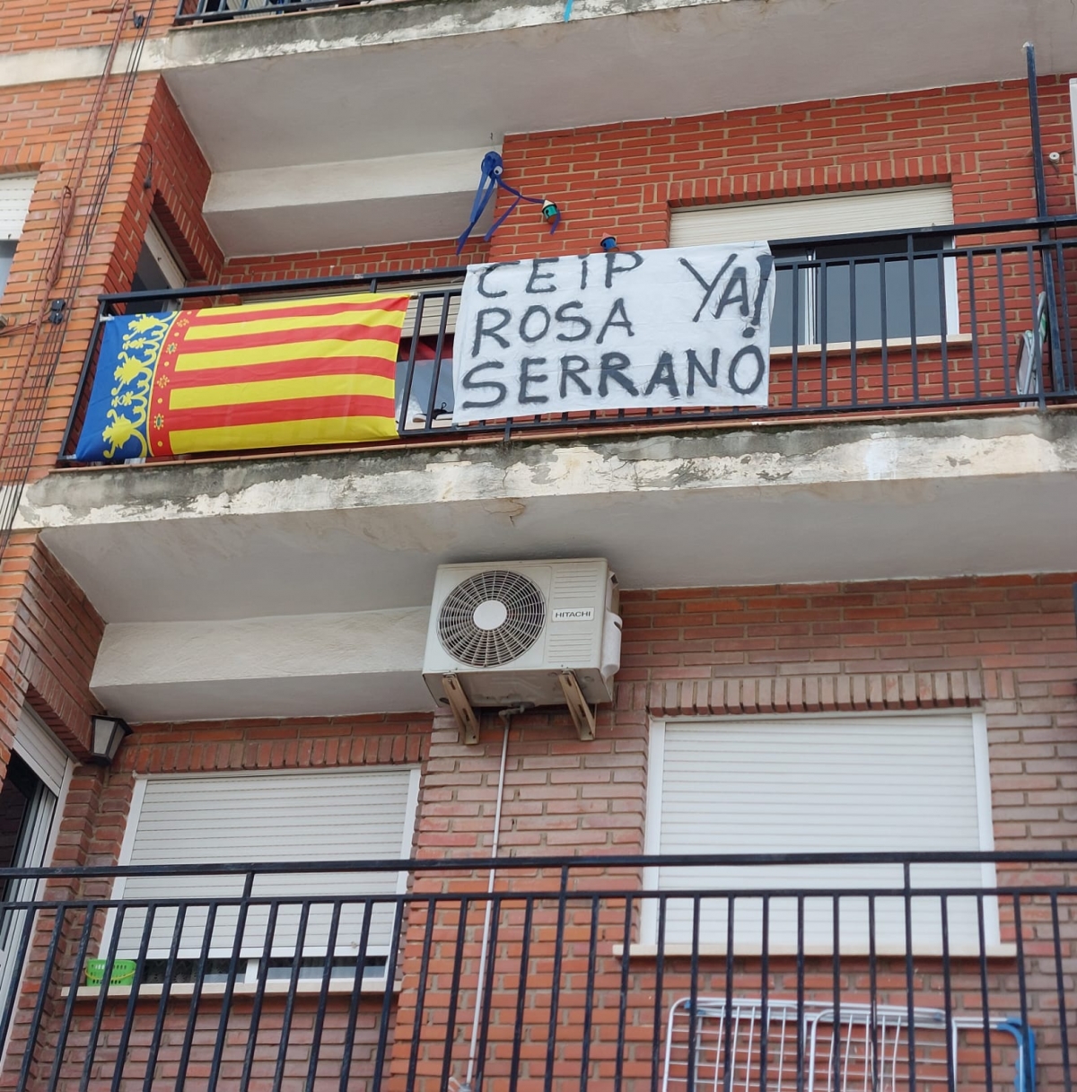 Pancarta colgada en un balcón de Paiporta que exige la reapertura del CEIP Rosa Serrano.
