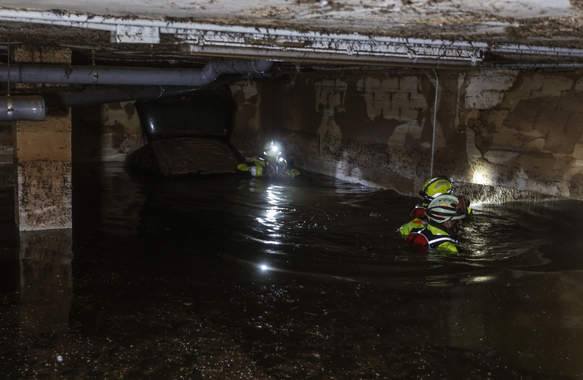 Varios bomberos buscando en los garajes afectados tras la Dana.