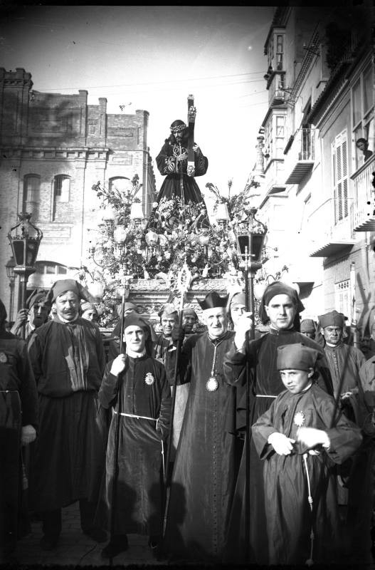 Nuestro Padre Jesús Nazareno, titular de la cofradía Marraja, acompañado por nazarenos y portapasos en Cartagena. 1920.