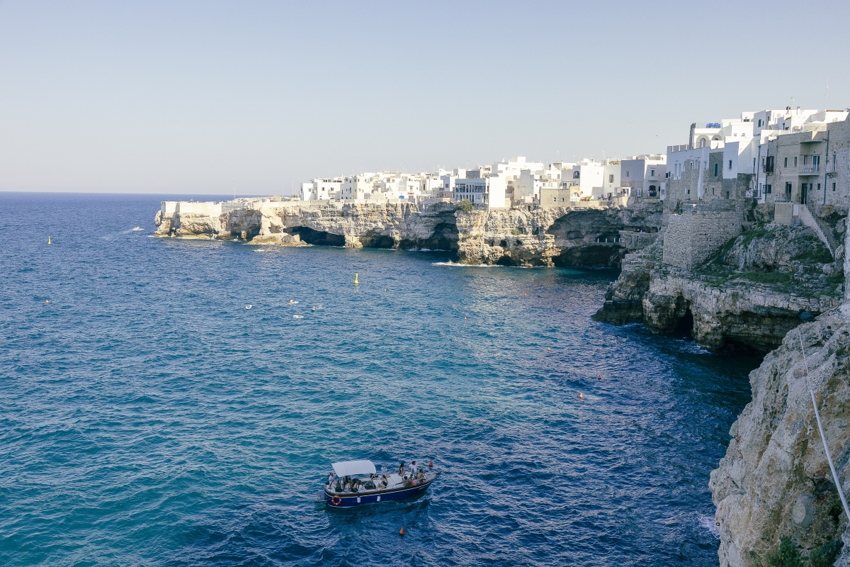 Los edificios blancos se asoman a los acantilados que caen sobre el mar en Polignano a Mare.