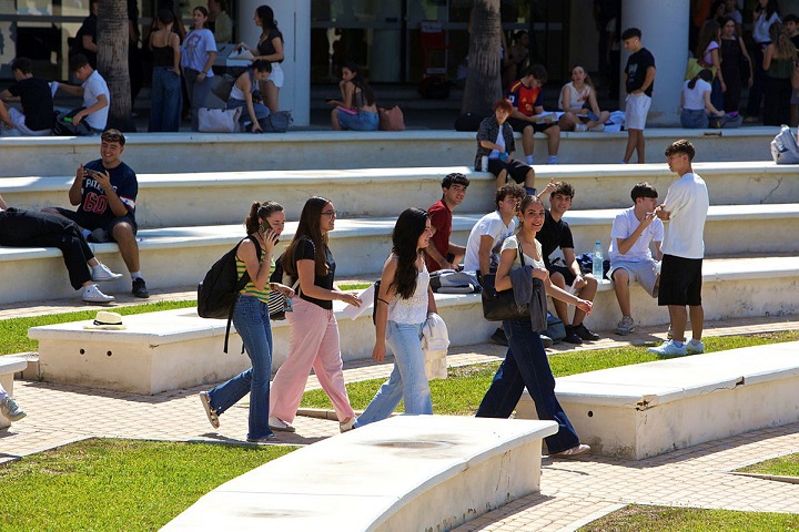 Personas caminando y intercambiando mensajes en un parque urbano soleado.