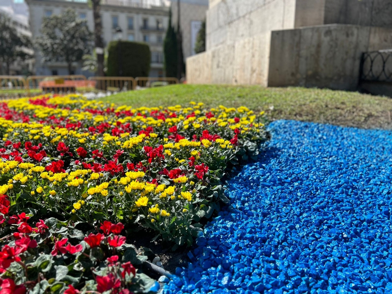 Piedras azules y flores rojas y amarillas decoran el Parterre para la ofrenda floral del 9 d'Octubre