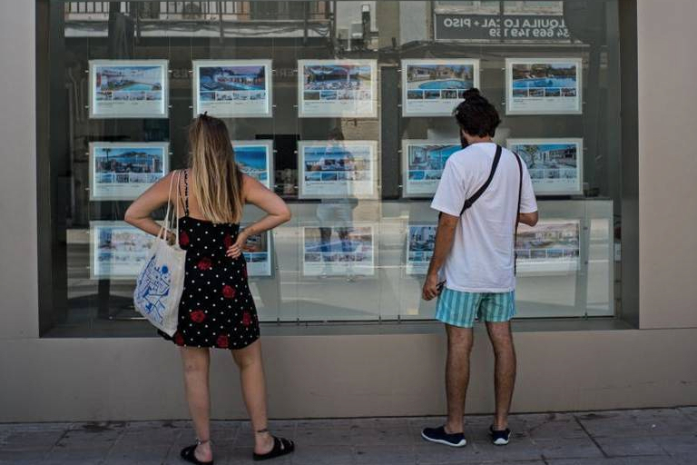Dos jóvenes observan el escaparate de una inmobiliaria. Foto: MATÍAS CHIOFALO  - 