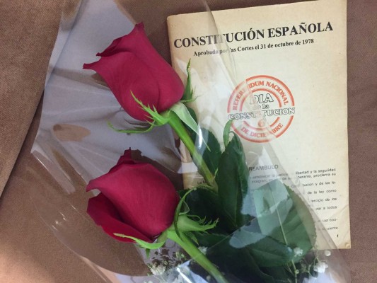 Dos rosas rojas y un ejemplar de la Constitución
