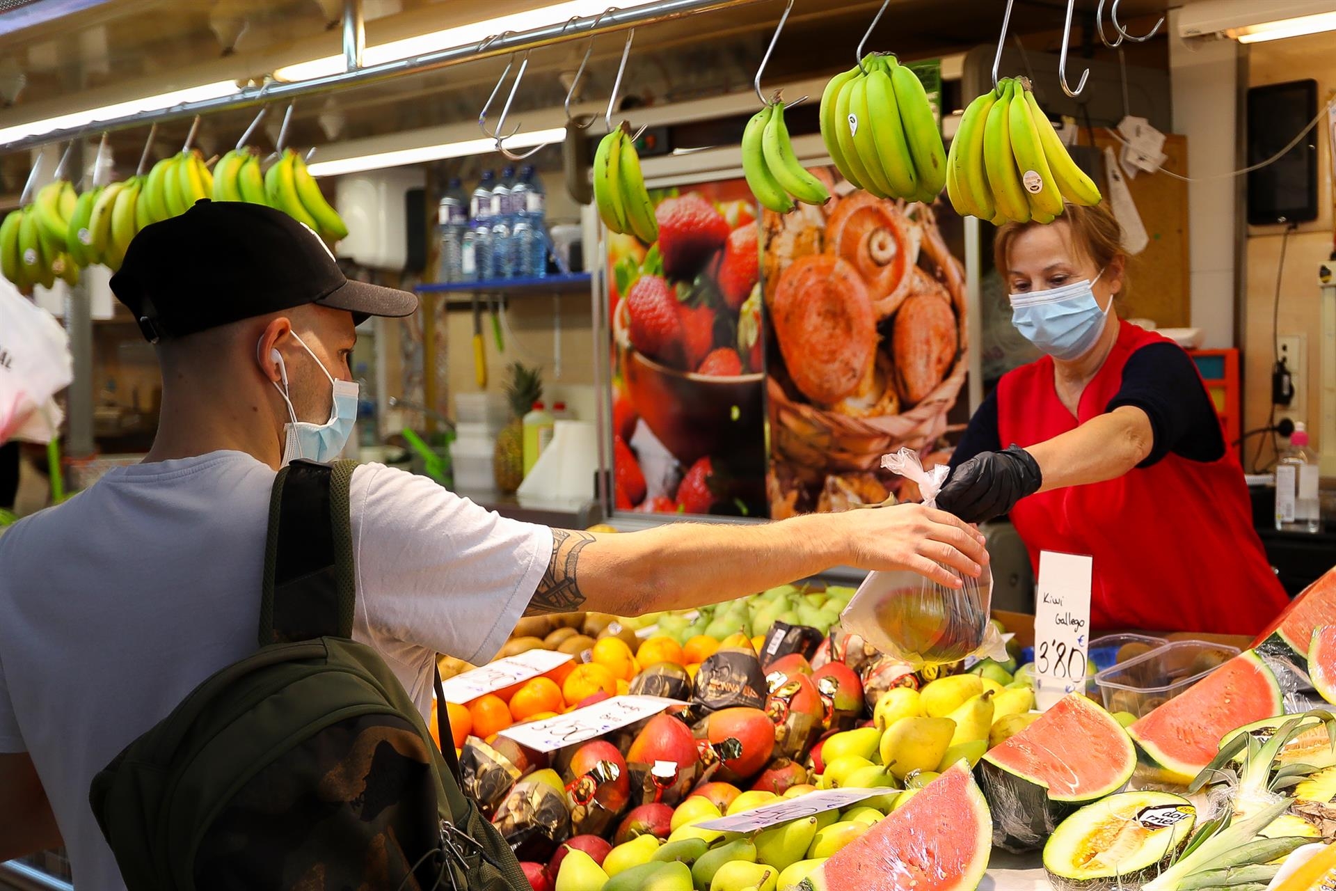Una trabajadora de una frutería del Mercado Central de Valencia atiende a un cliente. Foto: IVÁN TERRÓN/EP - 