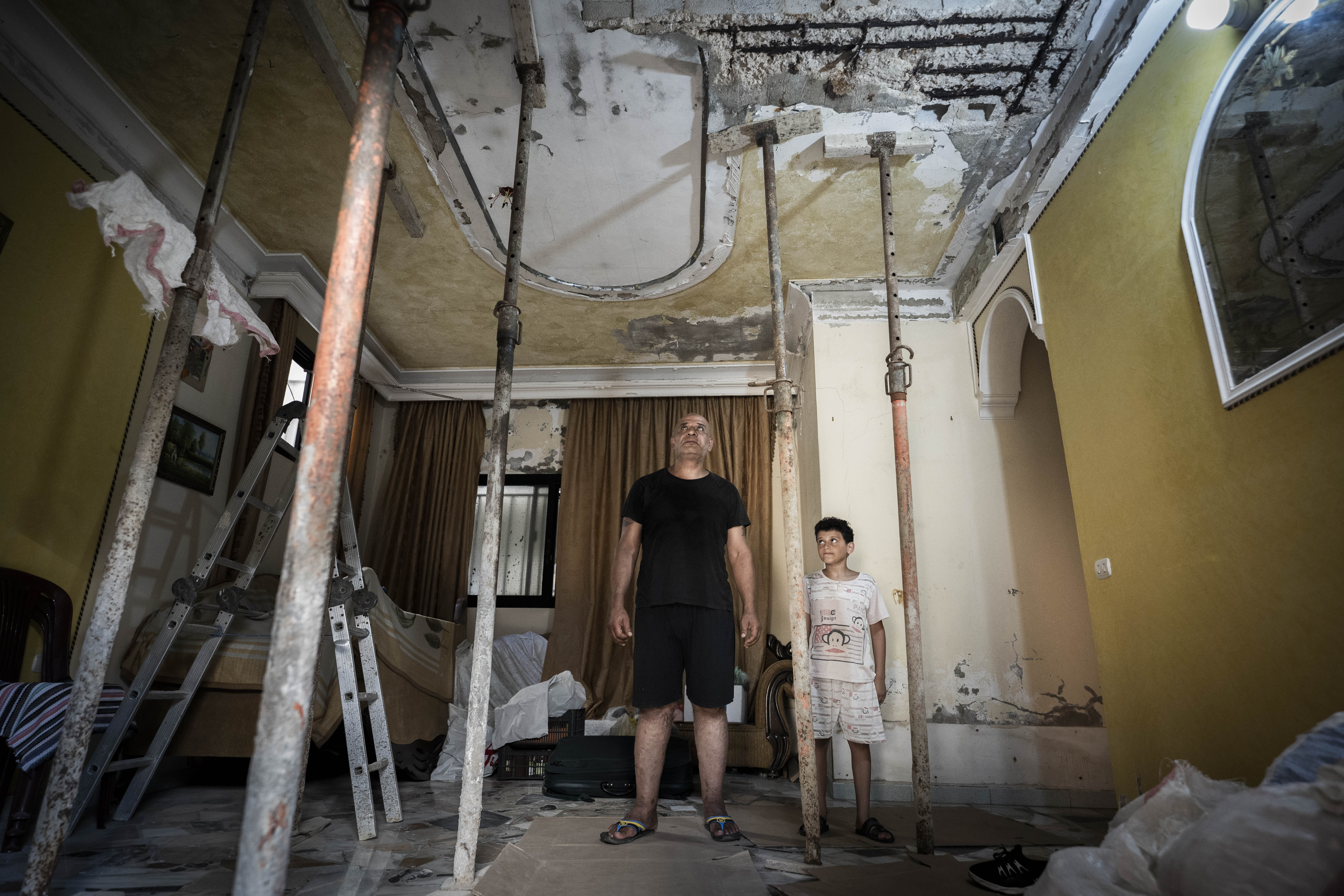 Yasser Abed Al-Halim observa con su hijo el techo de su casa. La onda expansiva de la explosión de agosto de 2020 en el puerto de Beirut provocó su hundimiento, campo de personas refugiadas palestinas de Burj El Barajneh, Beirut, 2020. Foto: GERMÁN C - 