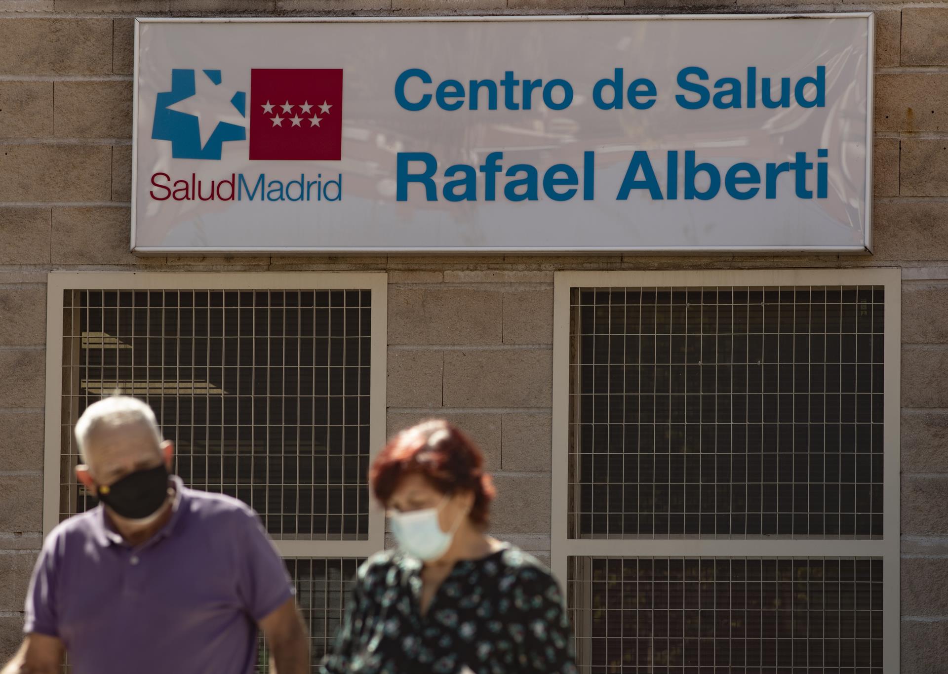 dos personas caminando al lado del Centro de Salud Rafael Alberto en el distrito de Puente de Vallecas Foto. - 