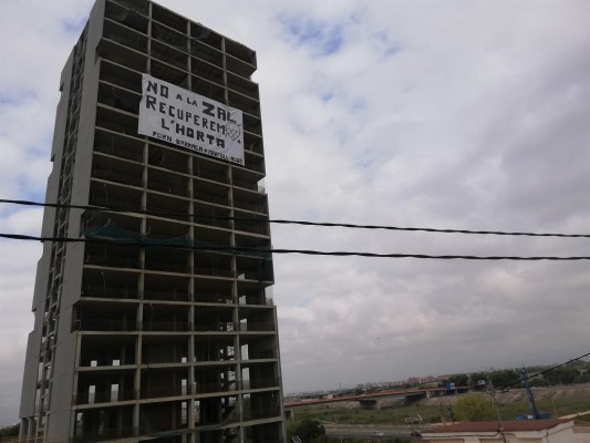 Activistas ecologistas cuelgan una pancarta gigante contra la ZAL en un edificio de Sociópolis