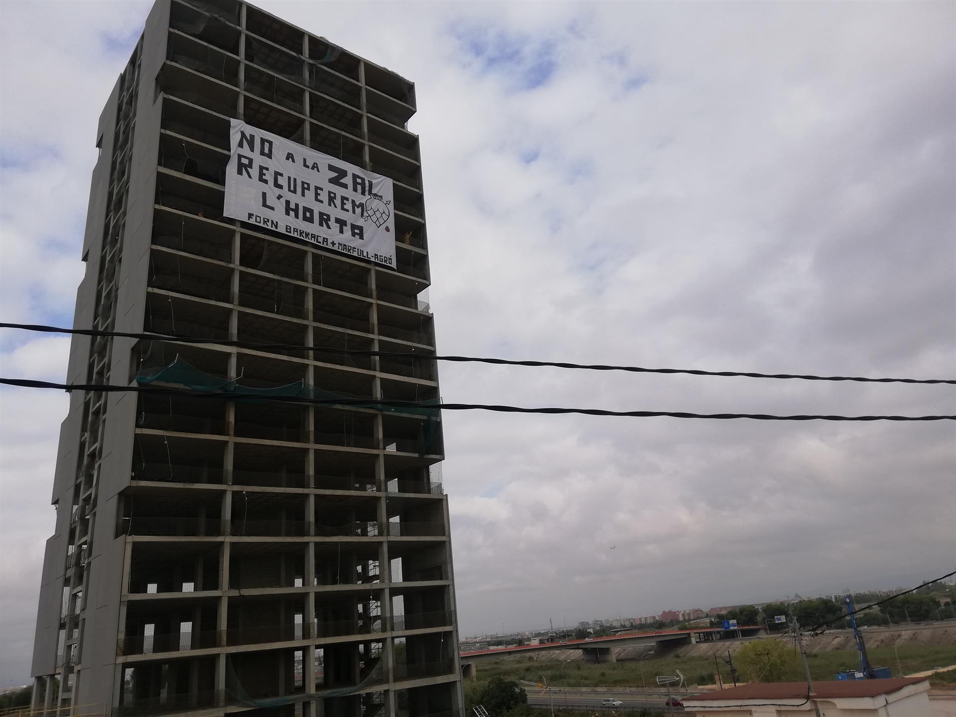 Activistas ecologistas cuelgan una pancarta gigante contra la ZAL en un edificio de Sociópolis