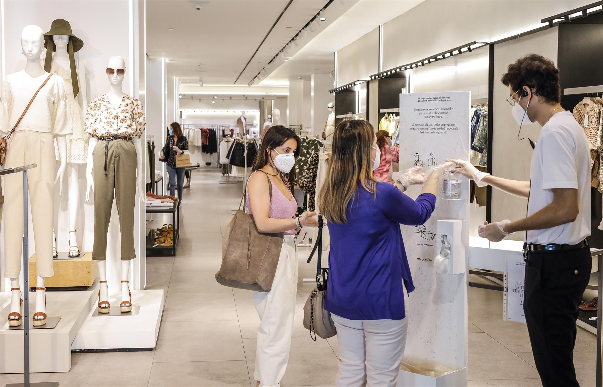 Dos clientas se desinfectan las manos con gel hidroalcohólico a la entrada de una tienda de ropa. Foto: ROBER SOLSONA (EP) - 