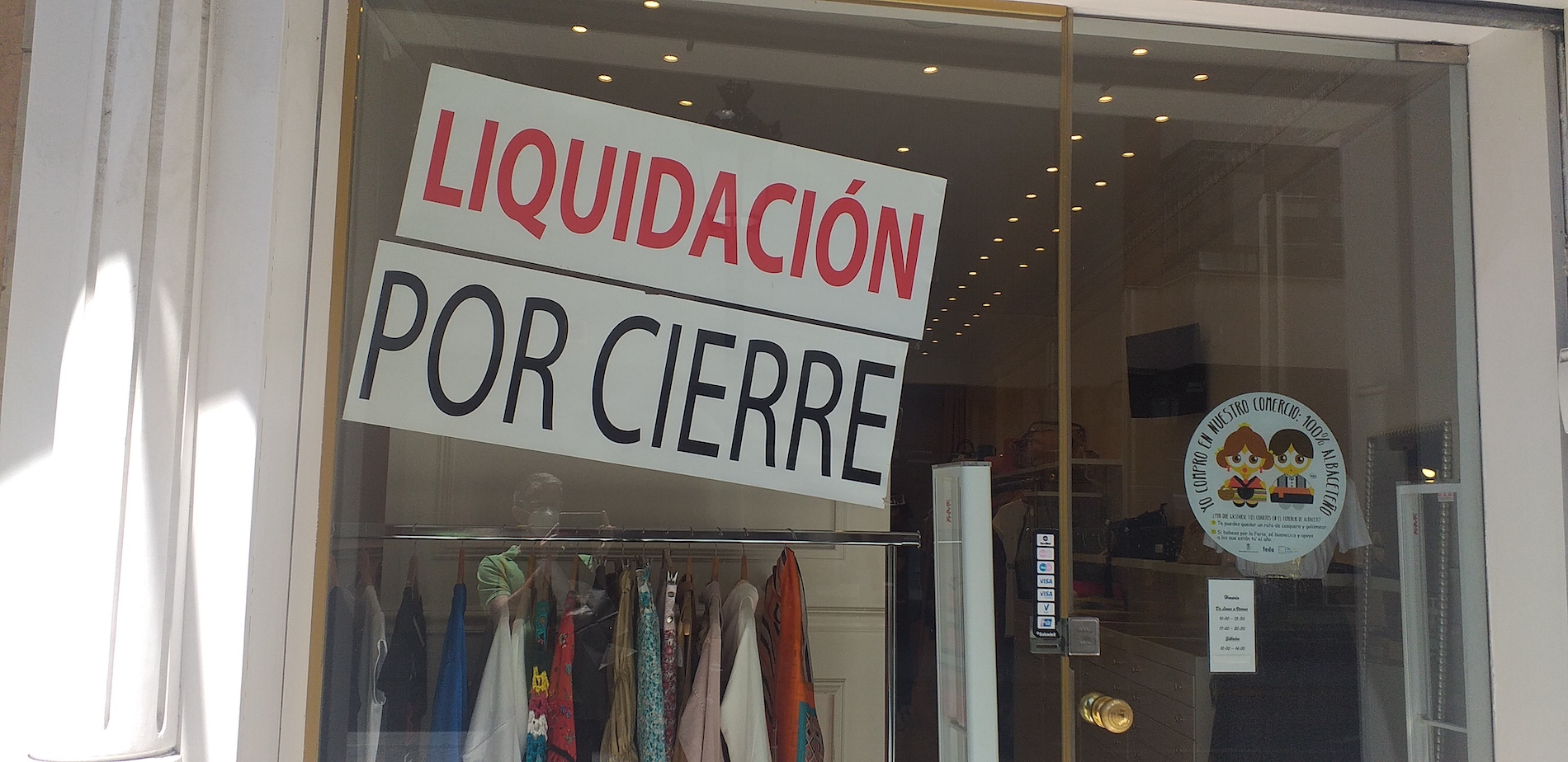 Una tienda de ropa coloca el cartel de 