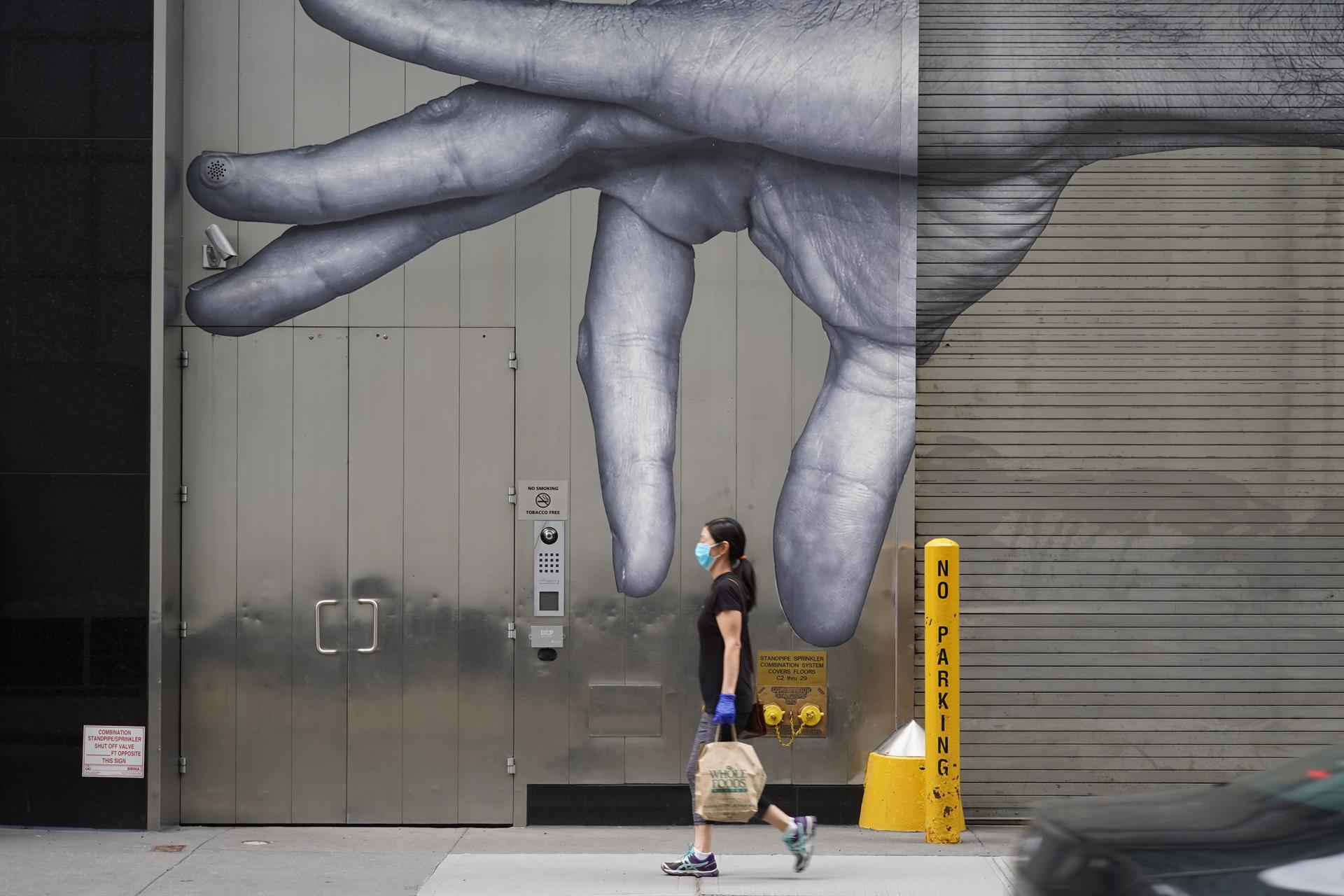 Una mujer con mascarilla paseando ante un mural en Nueva York - Foto: MOSKOWITZ/ZUMA Wire / DPA - 
