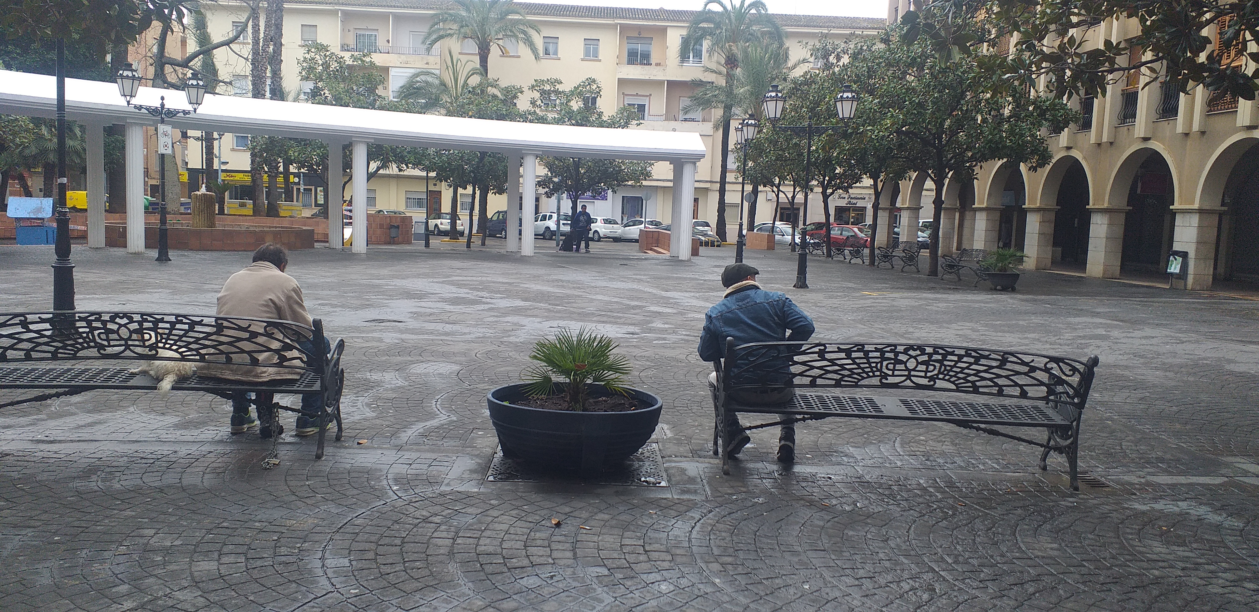 Dos hombres permanecen sentados en la plaza de un pueblo esta semana.  - 