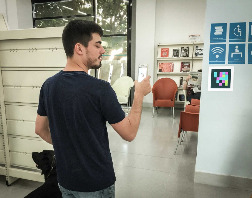 Un joven invidente utiliza la apliación de la UA con su móvil en la biblioteca. Foto: MVRLAB - 