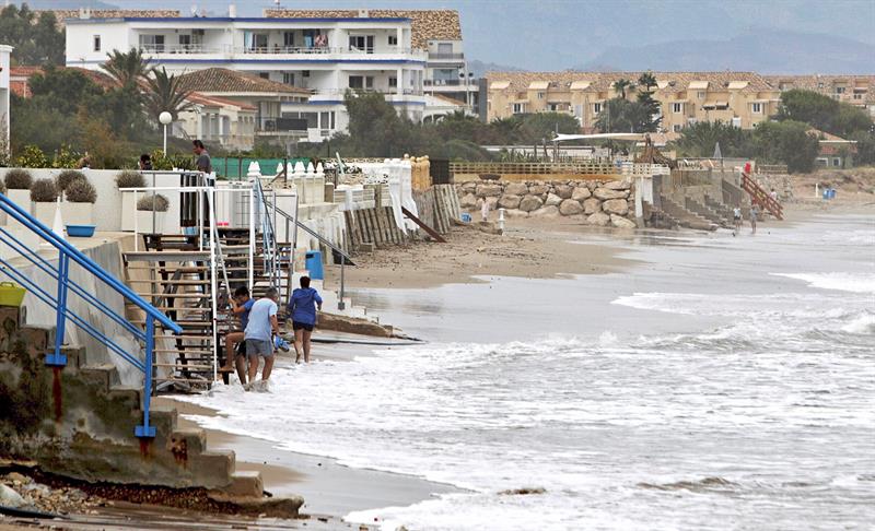 La lluvia ha hecho desaparecer casi por completo diversos tramos de la playa de Les Deveses en Dénia. Foto: EFE/Natxo Francés - 