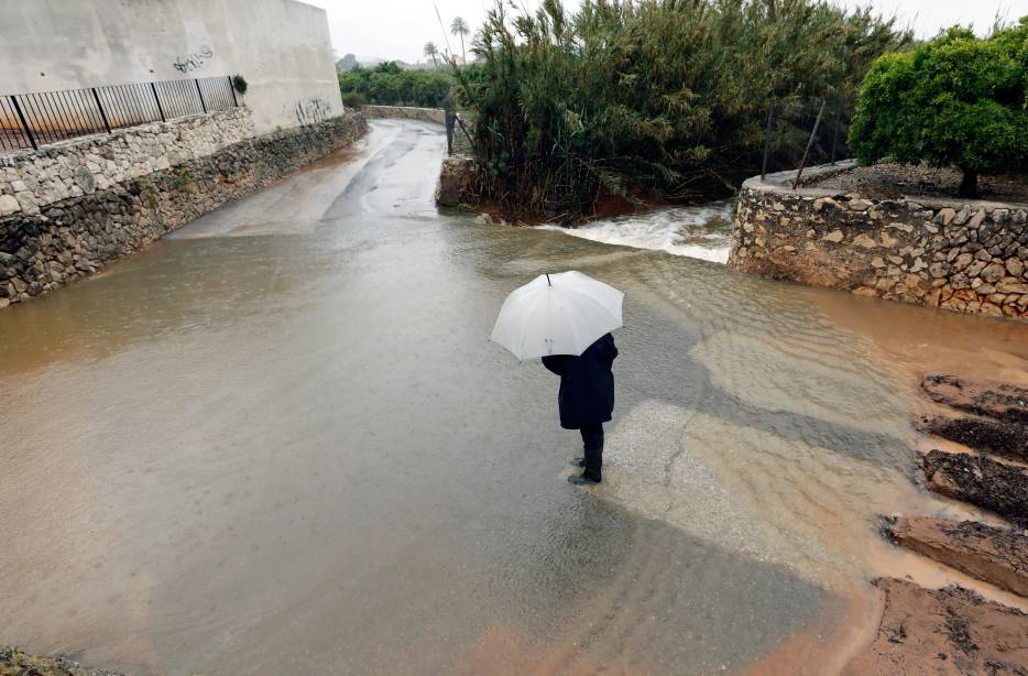 Un vecino de Xàbia intenta cruzar una calle anegada por la lluvia. Foto: PEPE OLIVARES - 