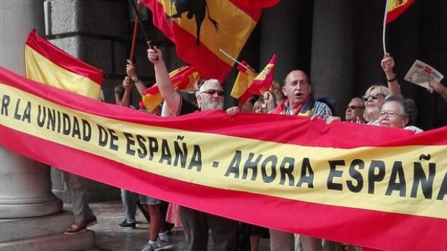 Decenas de personas despliegan una bandera gigante de España en la plaza del Ayuntamiento de València