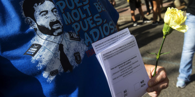 Un manifestante con una papeleta ilegal, una rosa y la imagen del Mayor Trapero. Foto: EFE - 