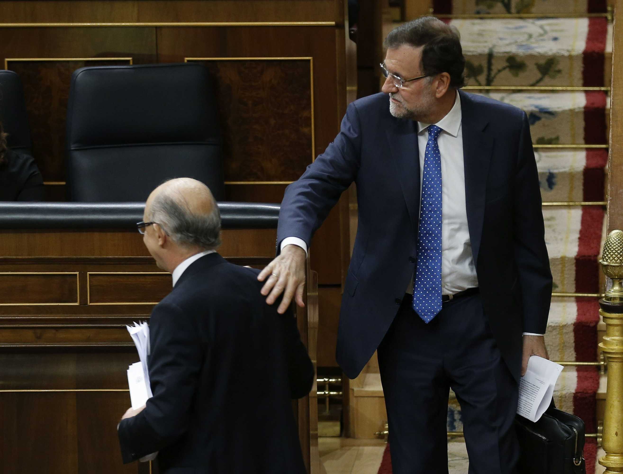El presidente del Gobierno, Mariano Rajoy, pone la mano en la espalda de Montoro. Foto: EFE - 