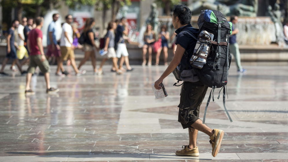 Un turista con mochila pasea por la plaza de la Virgen de València. Foto: EFE - 